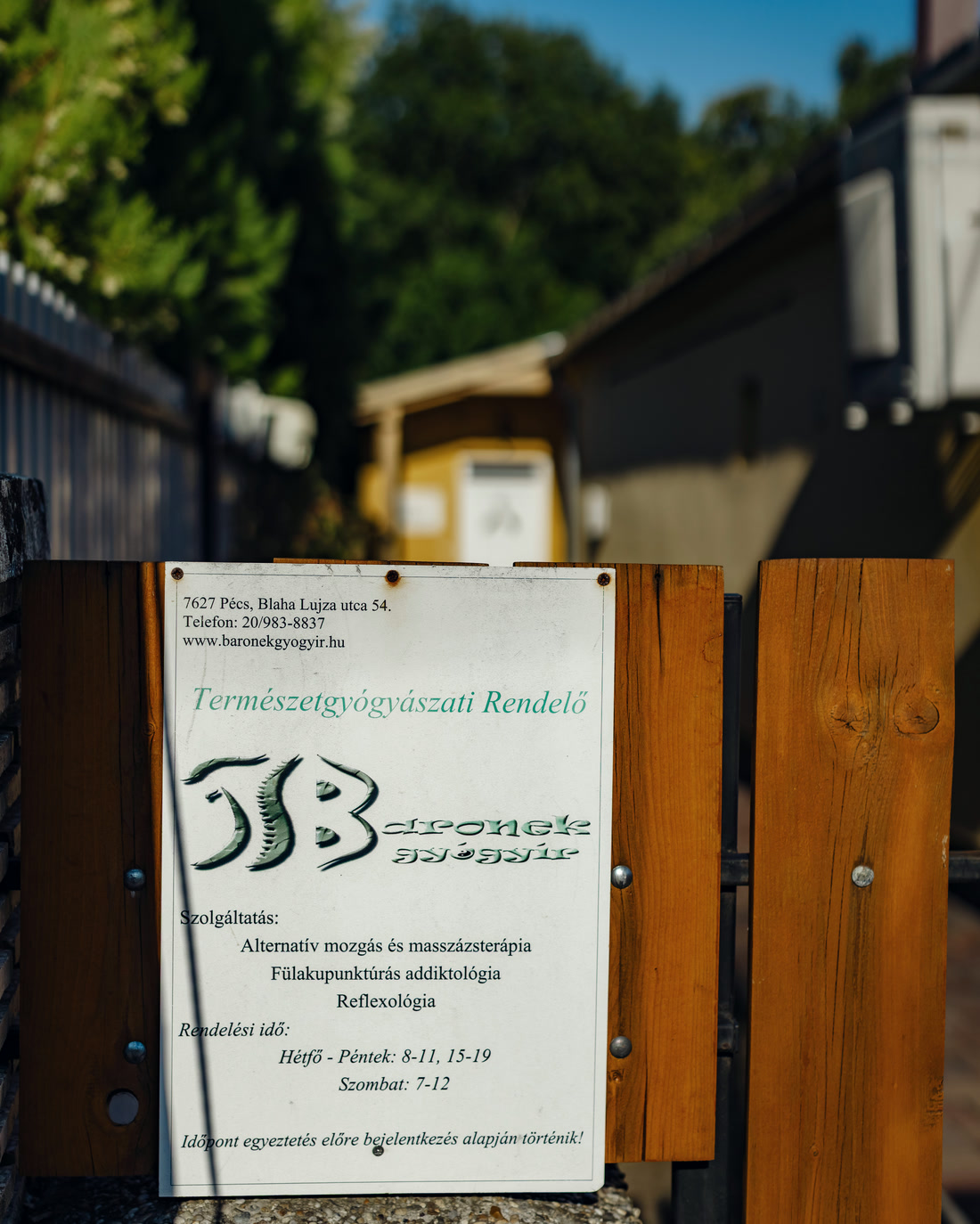 A fa kapu az utcáról, rajta a Baronek Gyógyír táblája